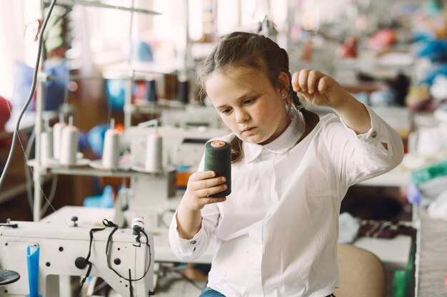 Little girl standing in the factory with a thread