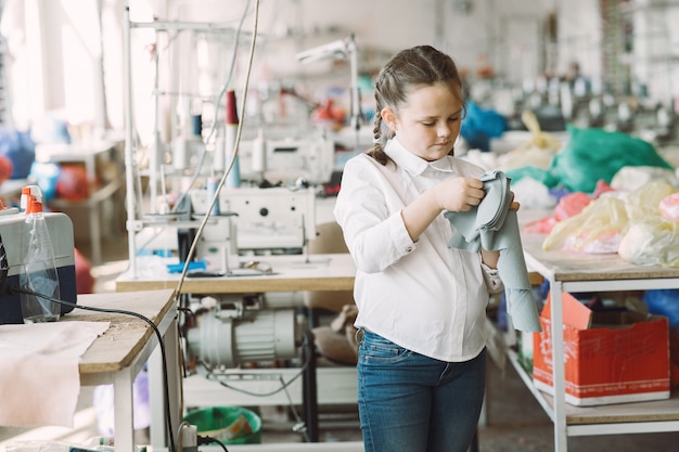 Little girl standing in the factory with a thread