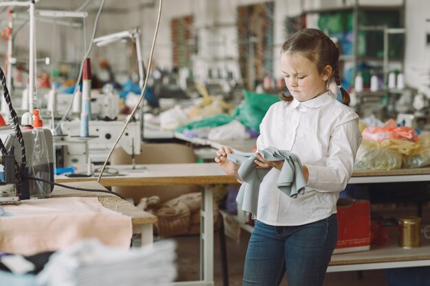 Little girl standing in the factory with a thread