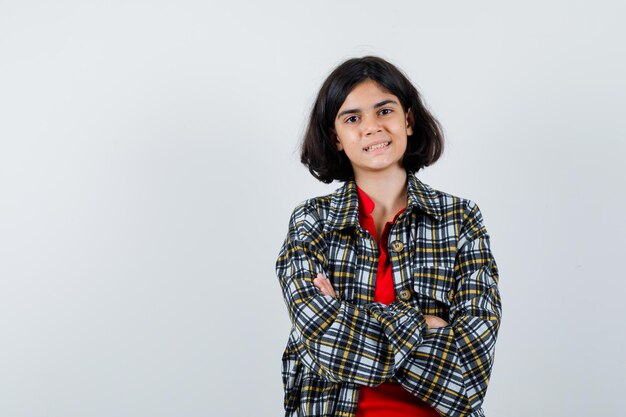 Little girl standing with crossed arms in shirt,jacket and looking optimistic. front view.