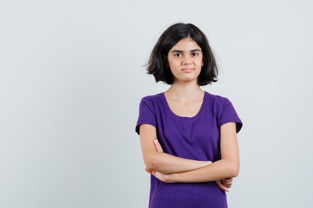 Little girl standing with crossed arms in t-shirt and looking confident.