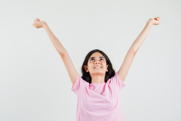 Little girl stretching arms in pink t-shirt and looking grateful , front view.