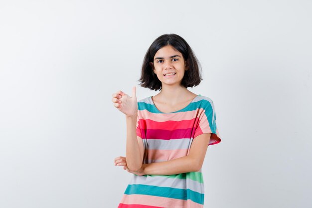 Little girl stretching hand as holding something in t-shirt, jeans and looking happy. front view.