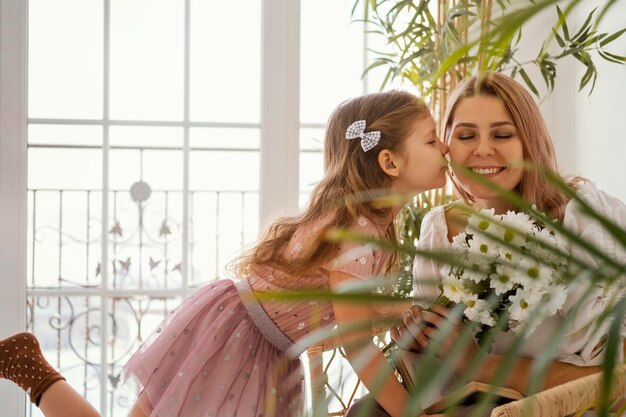 봄 꽃의 부케와 함께 그녀의 어머니를 놀라게하는 어린 소녀