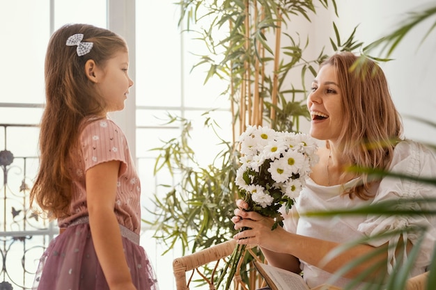 Little girl surprising mom with a bouquet of delicate spring flowers
