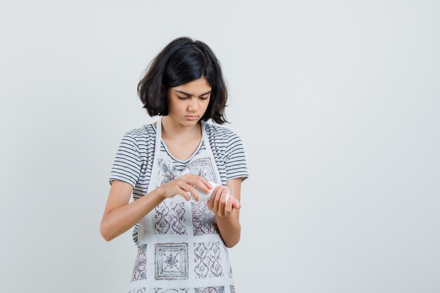 Tシャツを着た少女、薬瓶を開こうとしているエプロン、