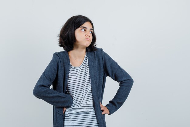 Little girl in t-shirt, jacket looking aside and looking hesitant ,