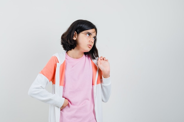 Little girl in t-shirt, jacket looking up and looking strict