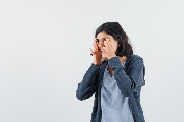 Little girl in t-shirt, jacket shouting or announcing something and looking happy