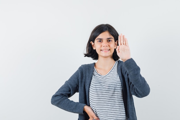 Little girl in t-shirt, jacket showing empty palm and looking confident