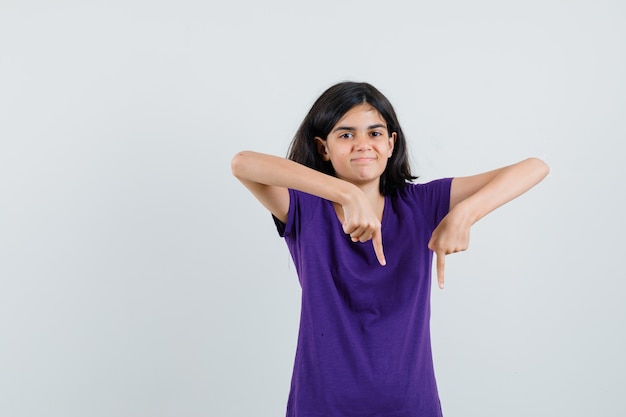 Little girl in t-shirt pointing down and looking happy ,