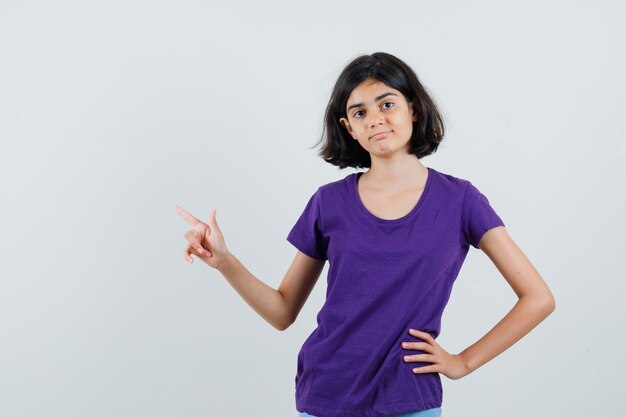 Little girl in t-shirt pointing at upper left corner and looking doubtful ,