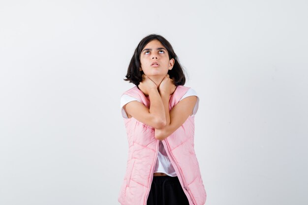 Little girl in t-shirt, puffer vest holding hands on the neck