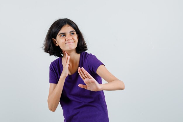 Little girl in t-shirt showing karate chop gesture and looking cheery ,