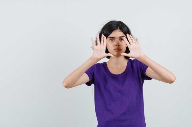 Little girl in t-shirt showing stop gesture and looking tired ,