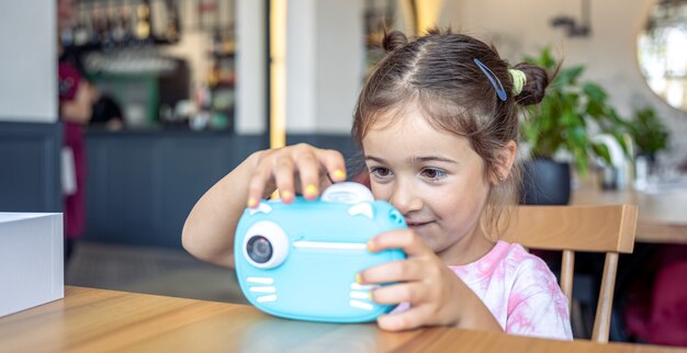 A little girl takes a photo on a camera for instant photo printing.