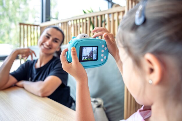 A little girl takes a photo of her mother on a camera for instant photo printing.