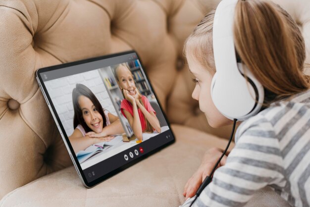 Little girl talking to her friends on a laptop in video call