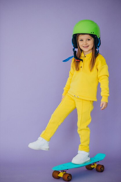 Little girl teaching to ride skateboard wearing helmet