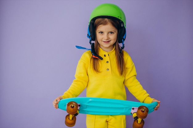 Little girl teaching to ride skateboard wearing helmet
