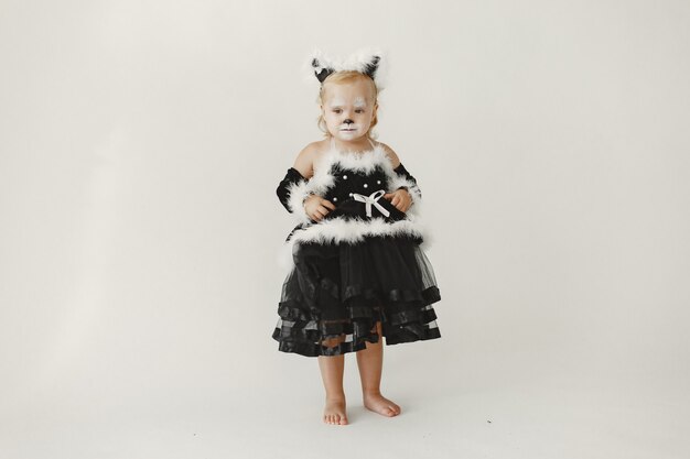 Little girl toddler dressed in black dress as a cat. Girl has her face painted like a cat's face