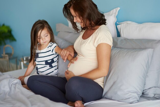 Little girl touching her mom's abdomen