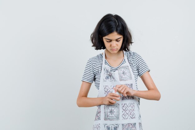 Tシャツの丸薬のボトルを開こうとしている少女