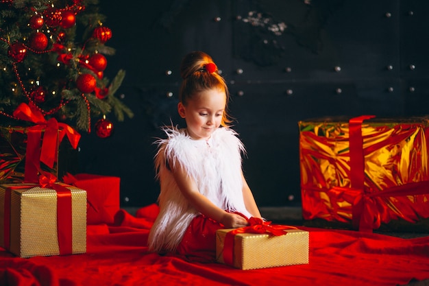 Little girl unpacking present by Christmas tree