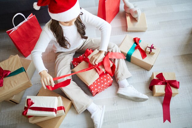 어린 소녀 unwrapping 크리스마스 선물, 행복한 하루
