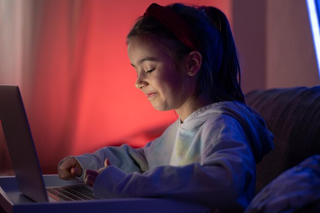 A little girl uses a laptop late at night