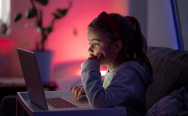 A little girl uses a laptop late at night