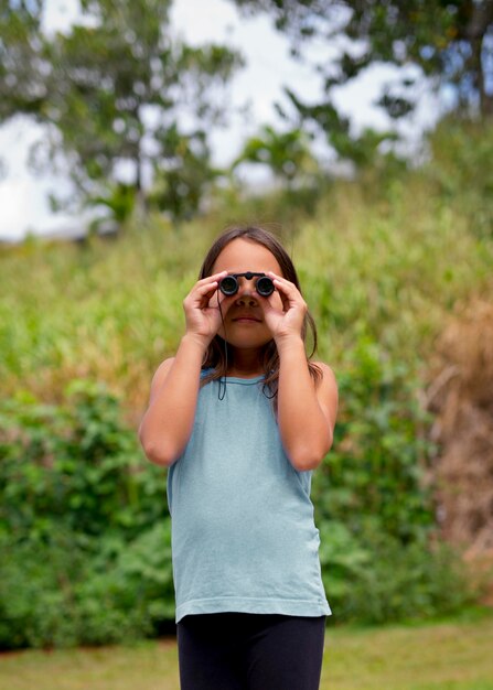 Little girl using binoculars in a treasure hunt