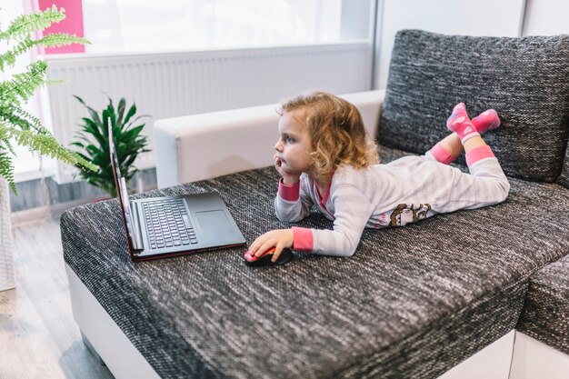 Little girl using laptop on couch