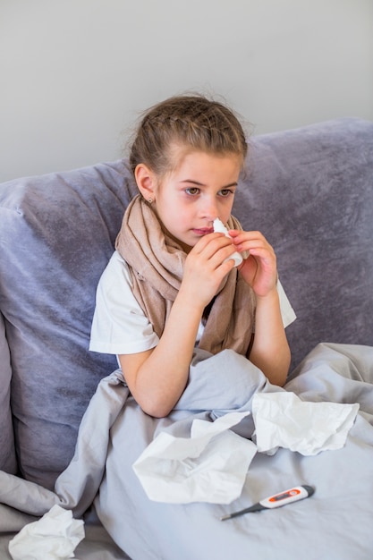 Little girl using nose spray