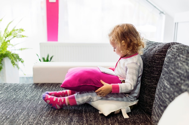 Little girl using tablet on sofa