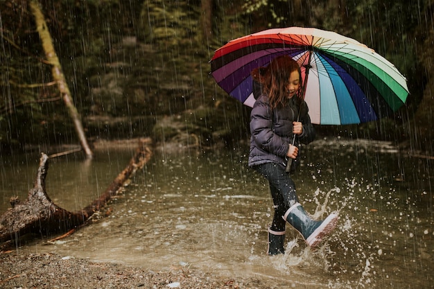 Free photo little girl using an umbrella in stream on a rainy day