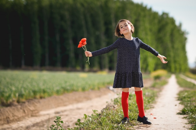 Little girl walking in nature field wearing beautiful dress