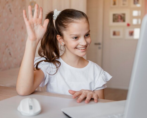 Little girl wanting to answer a question on online lessons