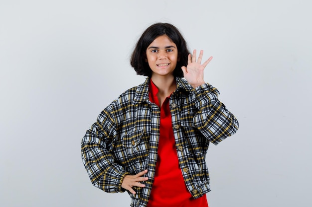 Little girl waving hand for greeting in shirt,jacket front view.