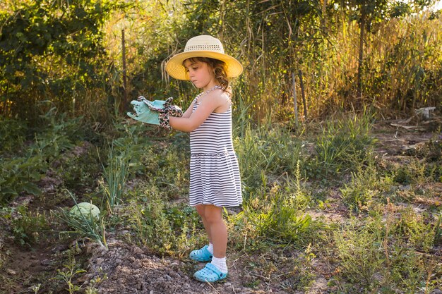 Little girl wearing hat standing in the field