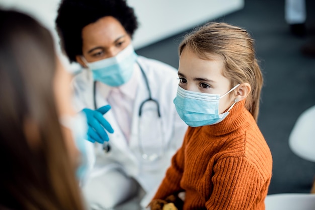 Little girl wearing protective face mask while being at medical clinic