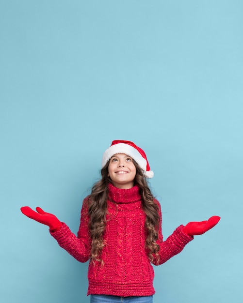 セーターとクリスマスの帽子を着ている少女