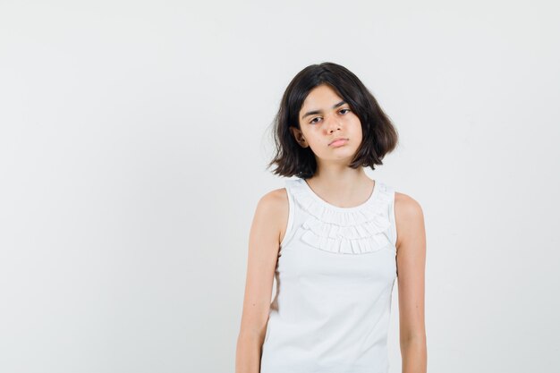 Little girl in white blouse looking at front and looking fatigued