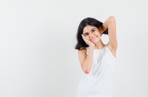 Little girl in white blouse posing while standing and looking cheerful , front view.