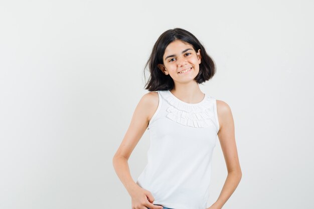 Little girl in white blouse posing while standing and looking cute , front view.