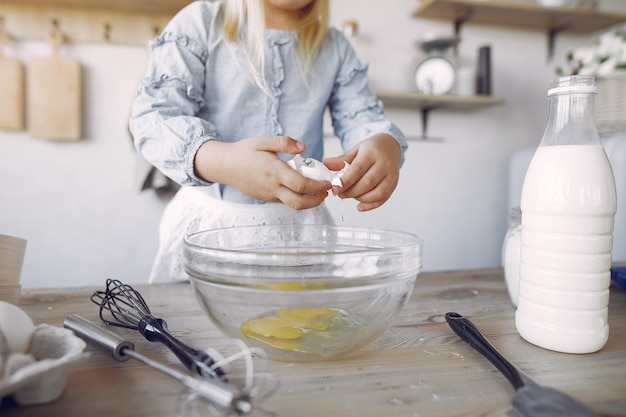 Free photo little girl in a white shef hat cook the dough for cookies