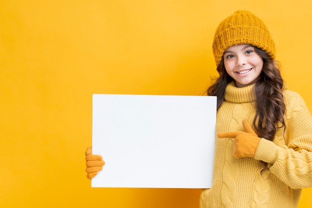 Little girl in winter clothes holding paper sheet