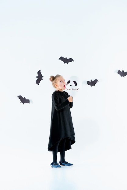 Little girl witch in black long dress and magical accessories. Halloween