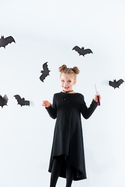 Little girl witch in black long dress and magical accessories. Halloween