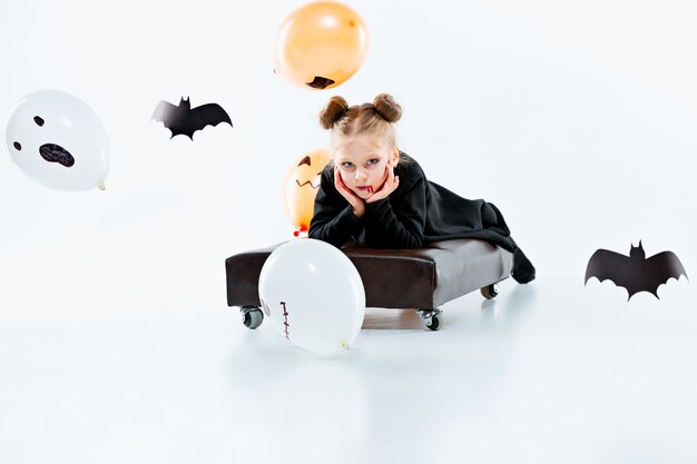 Little girl witch in black long dress and magical accessories. Halloween
